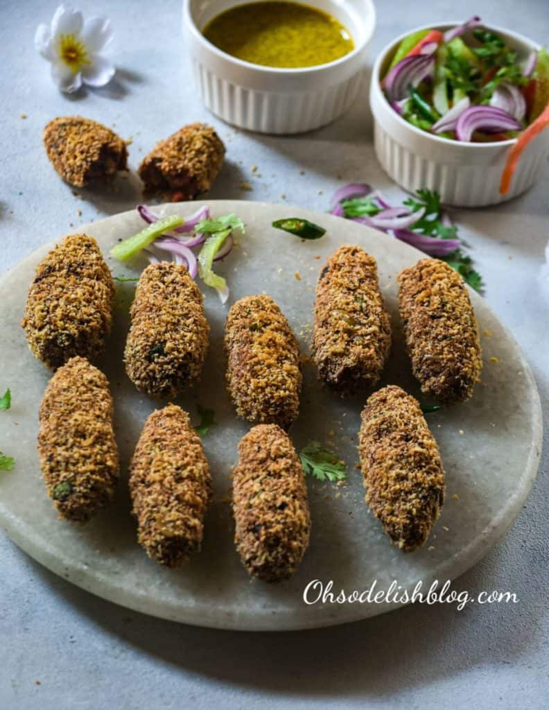 vegetable croquettes lined up on awhite background with some sliced onins and chillies